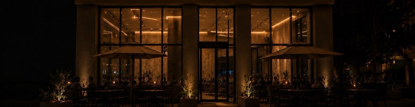 African Palace Restaurant at night: the lit sign above a glass frontage, with diners on the terrace.